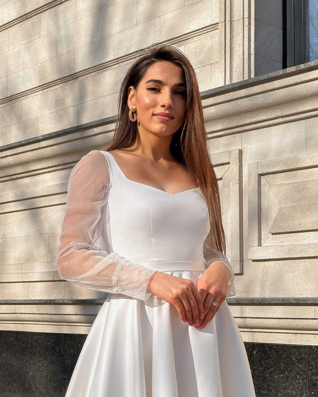 Rochie de mireasa albă lungă din satin cu mâneci transparente și șliț eleganți.