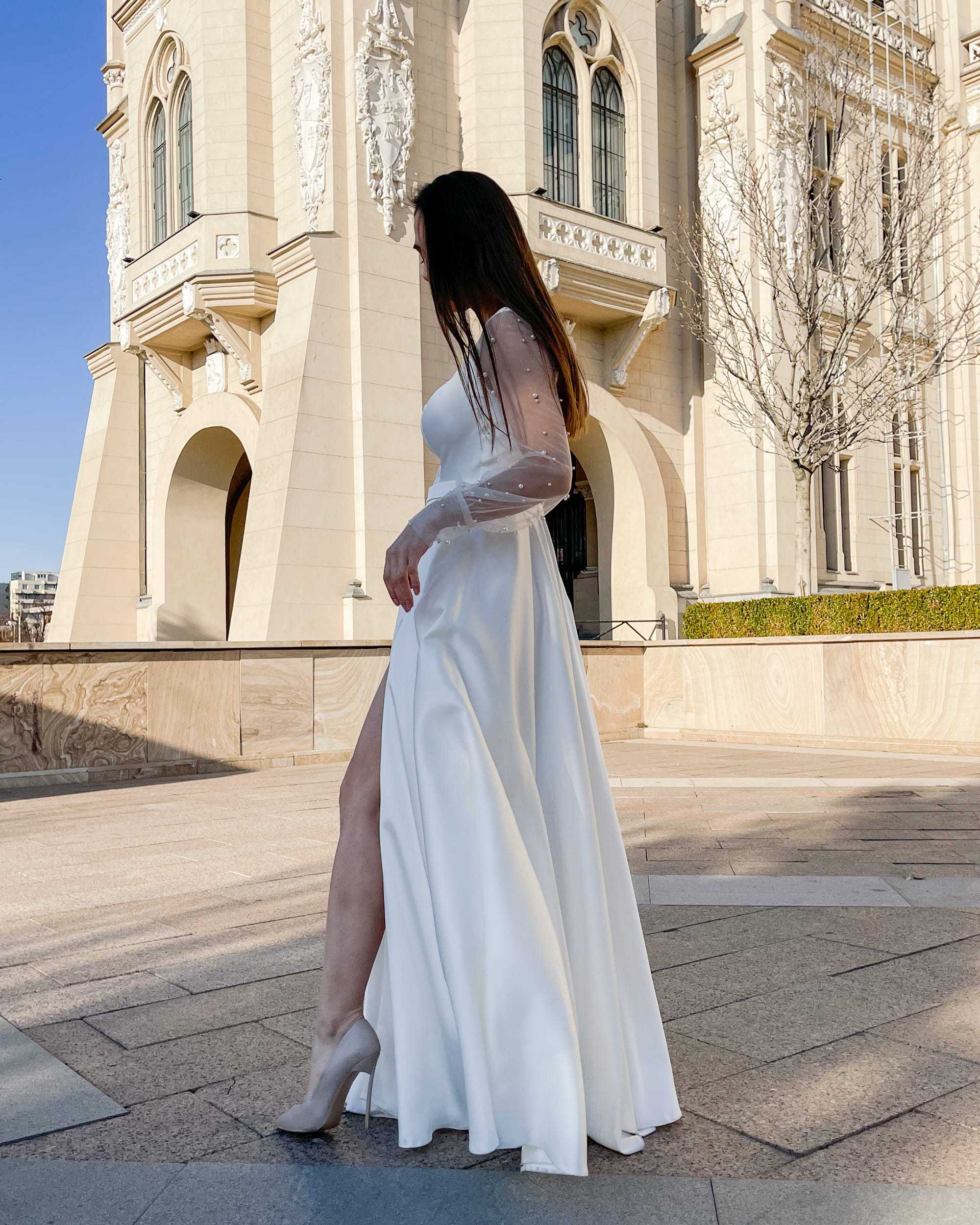 Rochie de mireasa lunga cu maneci din perle, decolteu in V, slit lateral, si nasturi eleganti la spate.