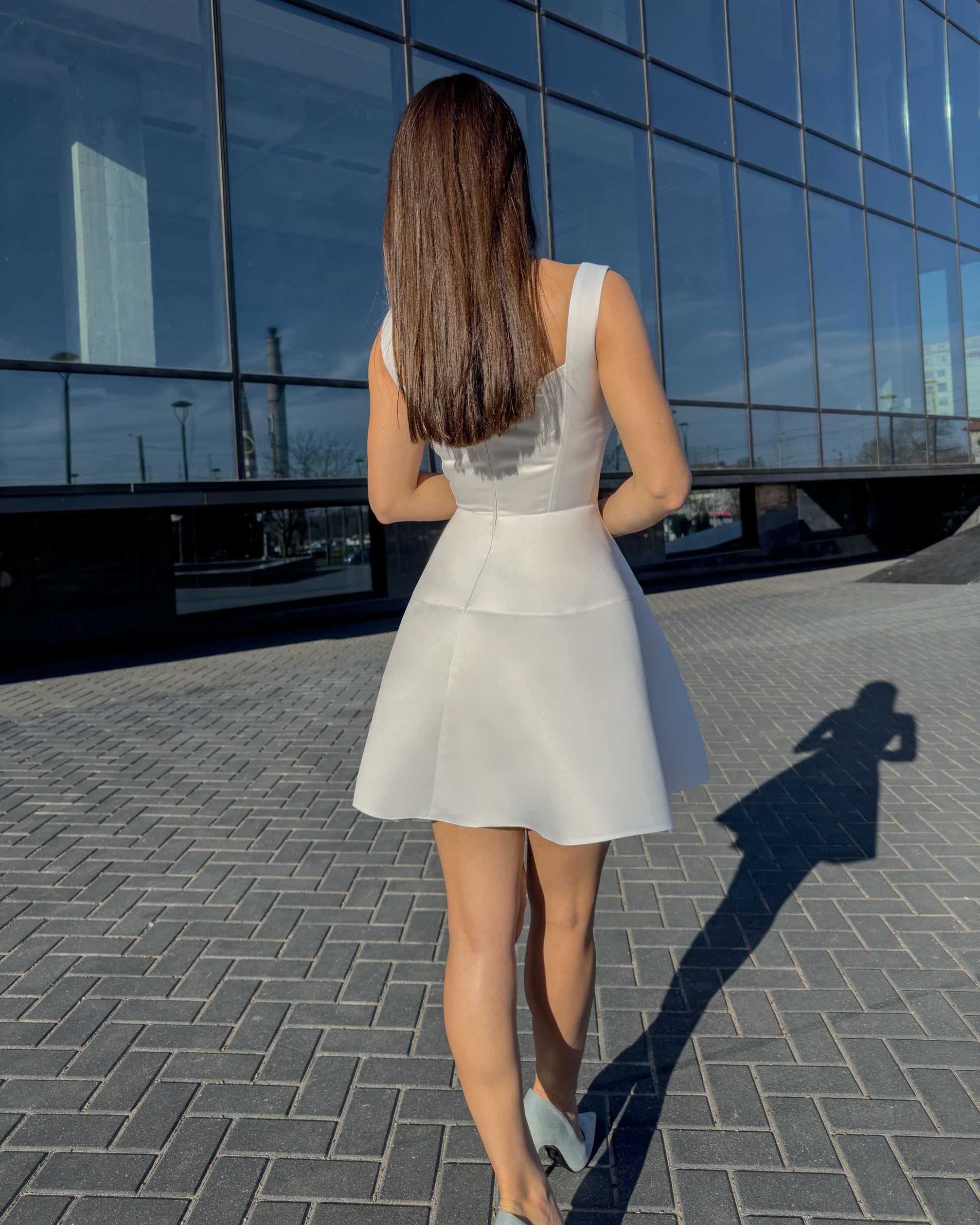 Rochie alba elegantă scurtă cu decolteu delicat și fermoar discret, ideală pentru evenimente speciale.