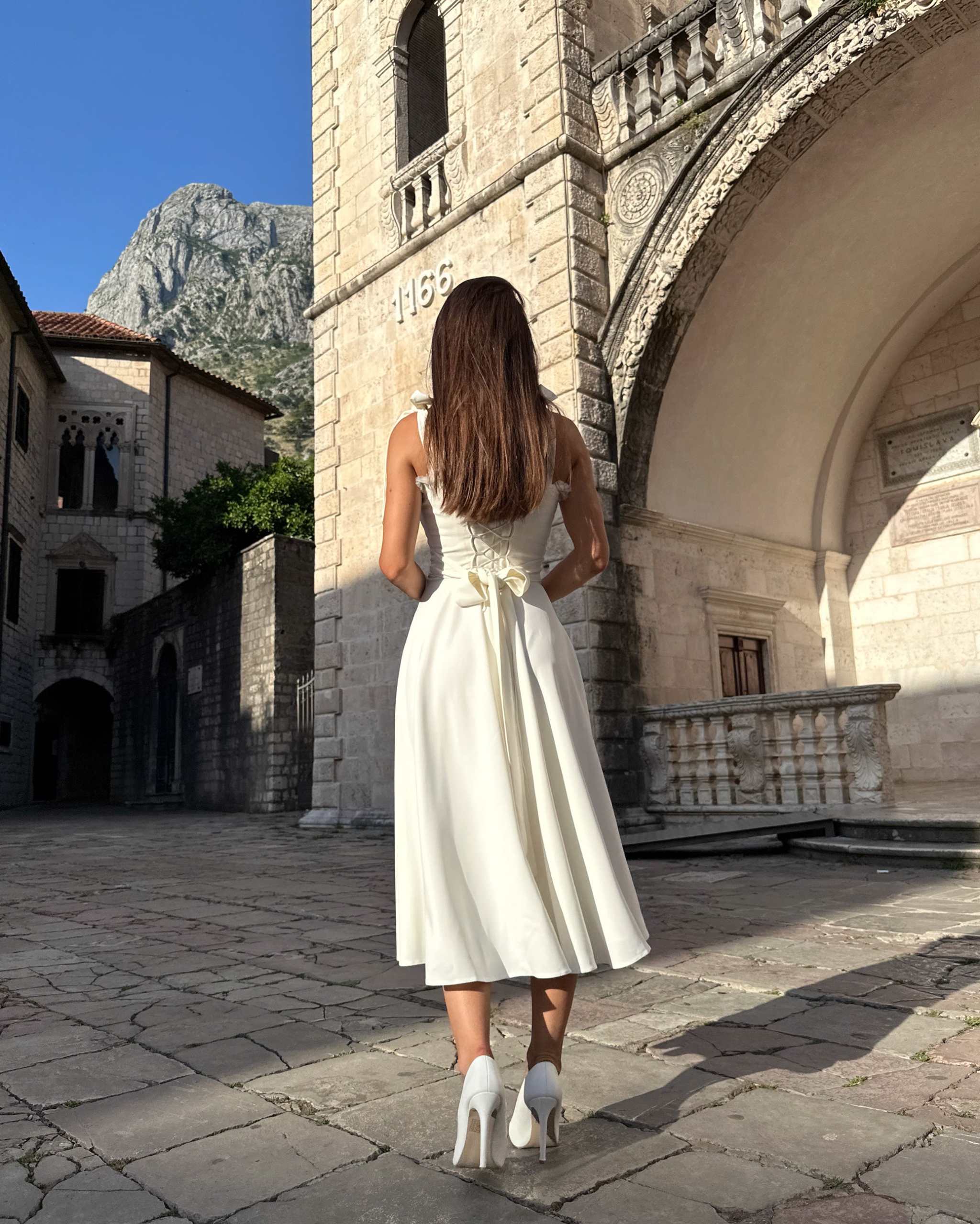 Rochie alba evazată cu corset reglabil și bretele ajustabile, vedere din spate.