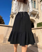 Fusta neagra midi din stofă elastică cu volane, design elegant și confortabil.