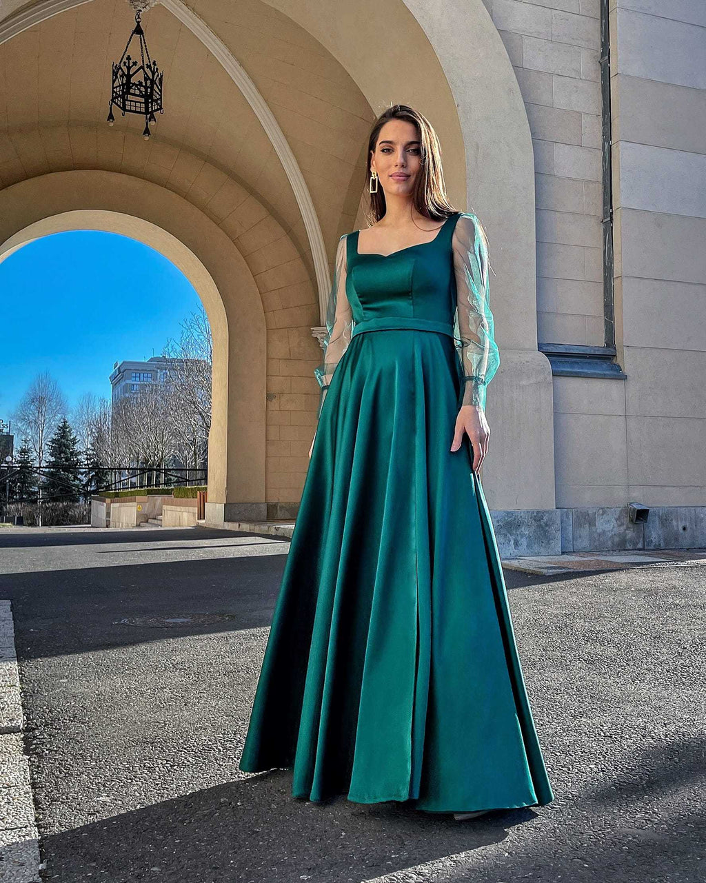 Rochie lunga verde smarald din satin cu mâneci transparente, decolteu pătrat și design elegant.