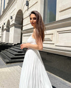 Rochie alba elegantă cu bretele și slit, accesorizată cu centură.