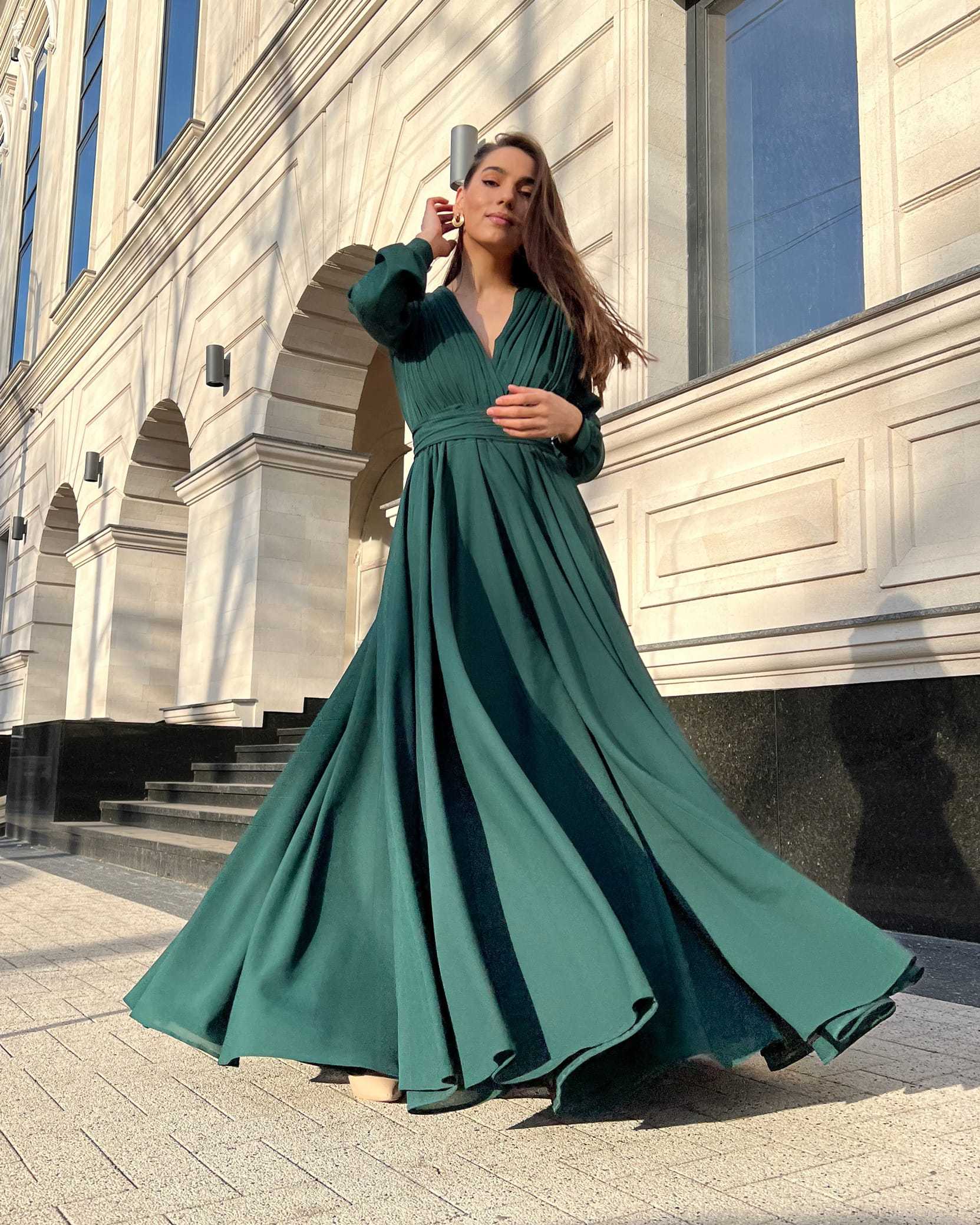 Rochie elegantă de seară lungă din voal verde, decolteu în V și pliuri, cu mâneci lungi și nasturi, ideală pentru evenimente formale.