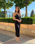 Rochie cocktail de seară neagră din satin elastic cu tăietură centrală și pliuri sofisticate.